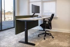 Werkplek met zit-sta bureau, bureaustoel en curved monitor in de Pieter IJzerman-kamer