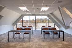Harry Frens kamer in cursusopstelling met rijen tafels en stoelen richting 75-inch scherm, ramen en uitzicht achterzijde — Mudde Kok FlexCentre