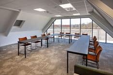 Harry Frens kamer in cursusopstelling voor 12 personen met tafels, stoelen, 75-inch scherm en ramen met daglicht — Mudde Kok FlexCentre