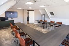 Harry Frens kamer in cursusopstelling voor 12 personen met tafels, stoelen, 75-inch scherm en ramen met daglicht — Mudde Kok FlexCentre