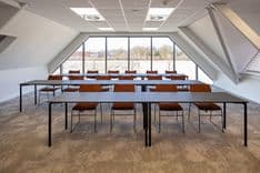 Harry Frens kamer in cursusopstelling voor 16 personen met tafels, stoelen, 75-inch scherm en ramen met daglicht — Mudde Kok FlexCentre