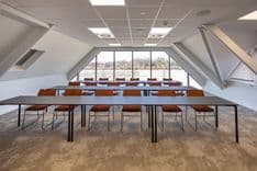 Harry Frens kamer in cursusopstelling voor 18 personen met tafels, stoelen, 75-inch scherm en ramen met daglicht — Mudde Kok FlexCentre