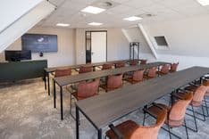 Harry Frens kamer in cursusopstelling voor 18 personen met tafels, stoelen, 75-inch scherm en ramen met daglicht — Mudde Kok FlexCentre