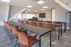 Harry Frens kamer in cursusopstelling voor 18 personen met tafels, stoelen, 75-inch scherm en ramen met daglicht — Mudde Kok FlexCentre