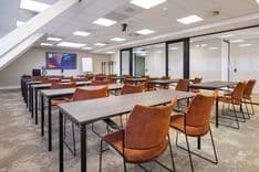 Huib van de Vecht zaal in cursusopstelling voor 30 personen met vaste werkplekken en scherm — Mudde Kok FlexCentre
