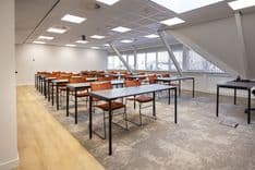 Huib van de Vecht zaal in cursusopstelling voor 16 personen met vaste werkplekken en scherm — Mudde Kok FlexCentre