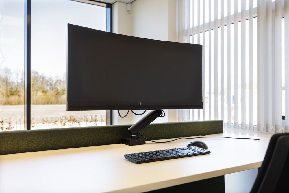 Close-up van bureau met 34-inch curved monitor in de Pieter IJzerman-kamer