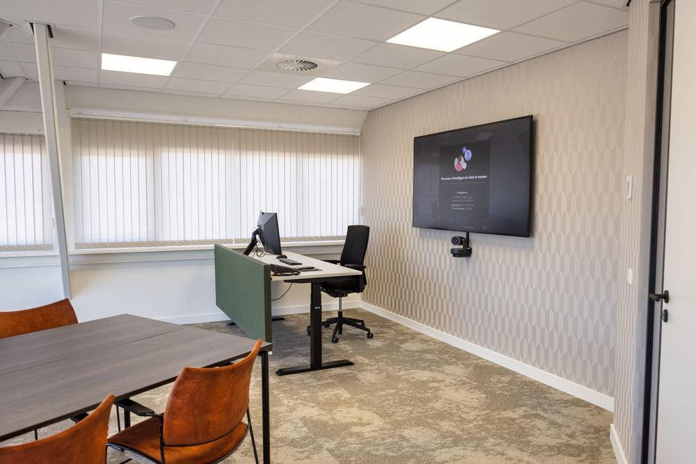 Vergaderruimte Harry Frens met 75-inch scherm en werkplekken — Mudde Kok FlexCentre