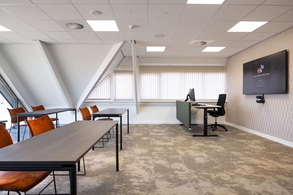Harry Frens kamer in cursusopstelling met tafels, stoelen en 75-inch scherm — Mudde Kok FlexCentre