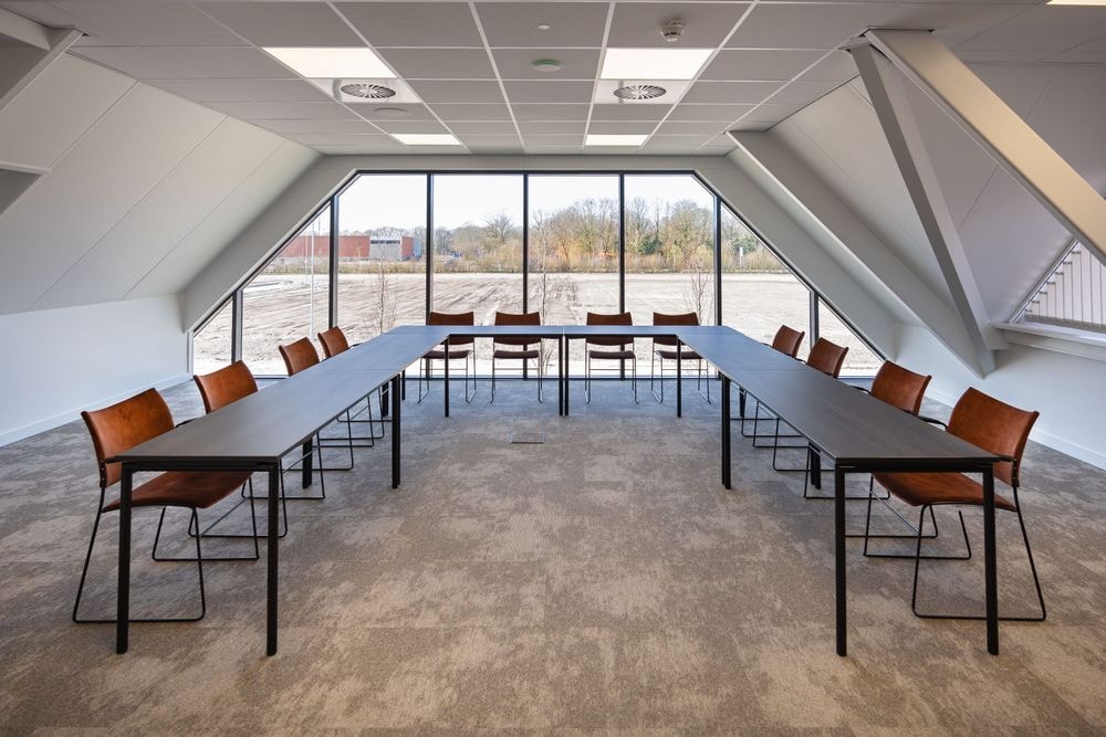 Harry Frens kamer in cursusopstelling voor 12 personen met tafels, stoelen, 75-inch scherm en ramen met daglicht — Mudde Kok FlexCentre
