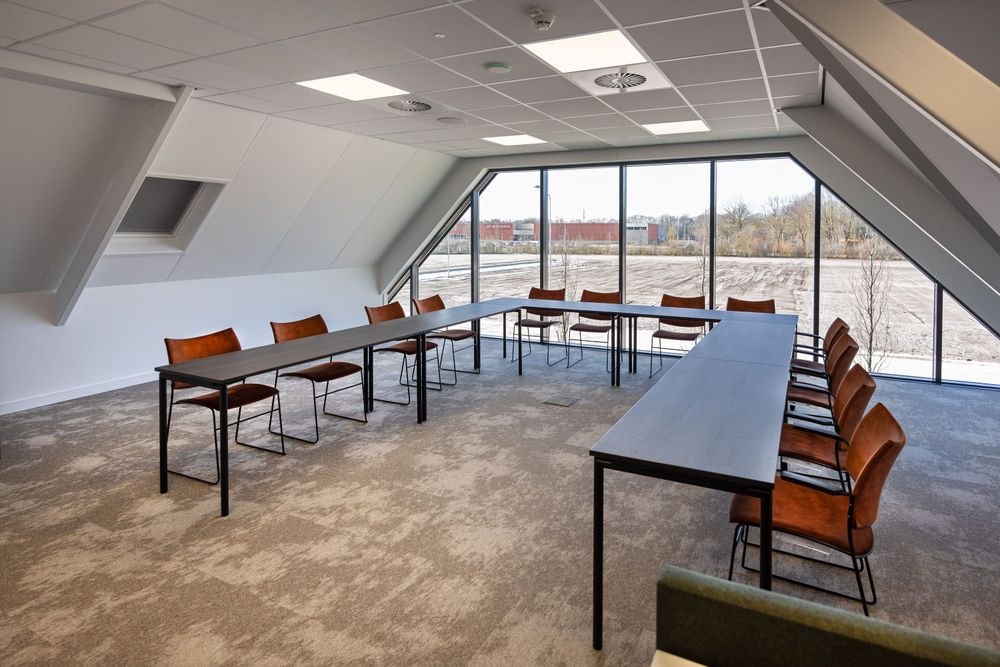 Harry Frens kamer in cursusopstelling voor 12 personen met tafels, stoelen, 75-inch scherm en ramen met daglicht — Mudde Kok FlexCentre