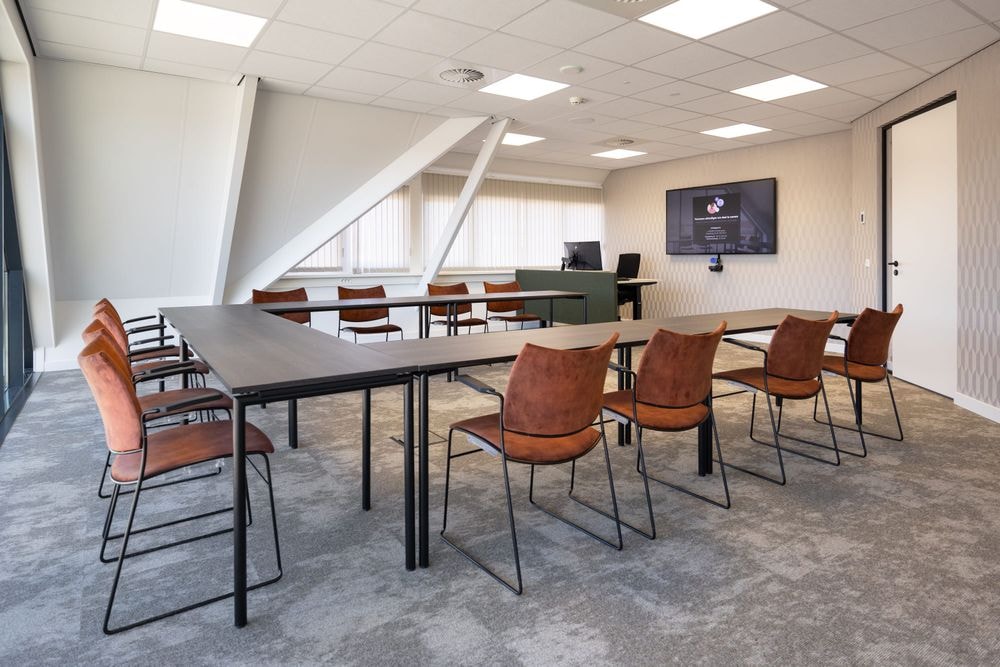 Harry Frens kamer in cursusopstelling voor 12 personen met 75-inch scherm en ramen met uitzicht — Mudde Kok FlexCentre