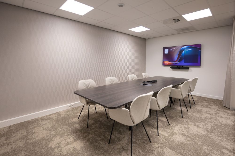 Overzicht van vergaderruimte Arthur Briët met 8 stoelen en 65-inch scherm