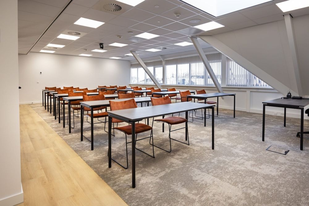 Huib van de Vecht zaal in cursusopstelling voor 20 personen met vaste werkplekken en scherm — Mudde Kok FlexCentre