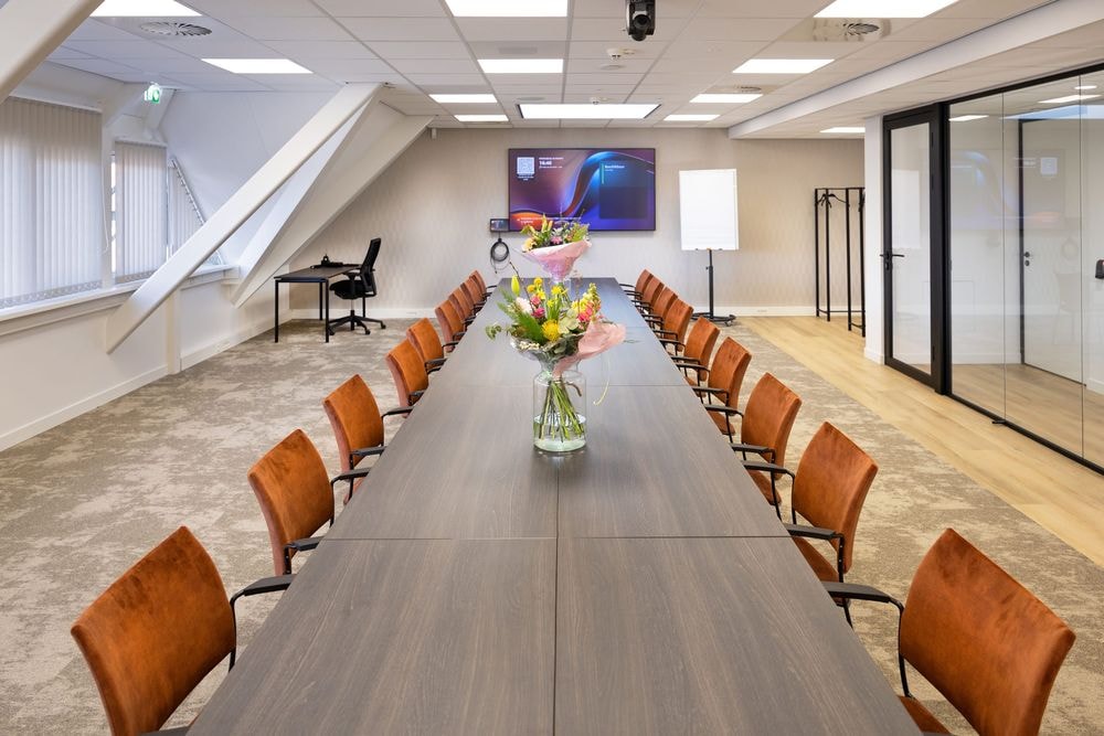 Huib van de Vecht zaal in vergaderopstelling voor 16 personen met 86-inch scherm — Mudde Kok FlexCentre