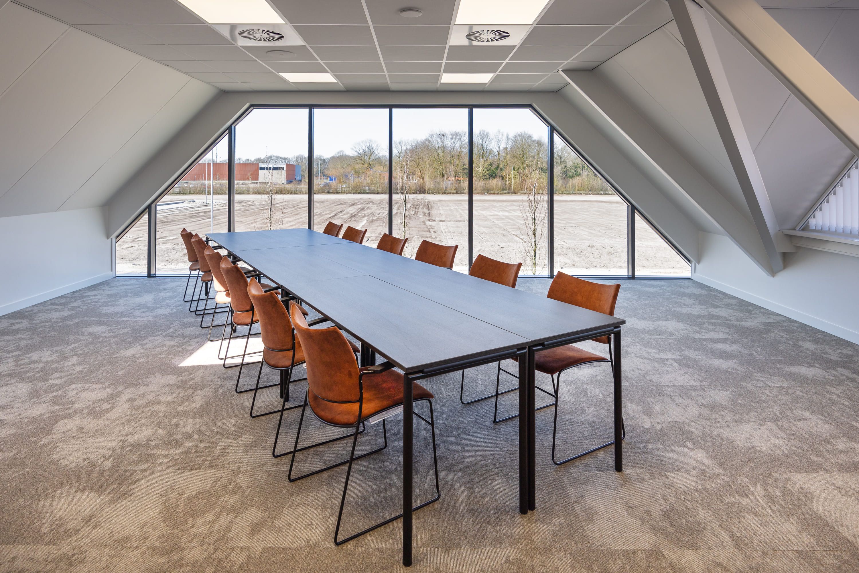 Vergaderruimte Harry Frens met lange tafel, 12 stoelen en veel daglicht door grote ramen — Mudde Kok FlexCentre
